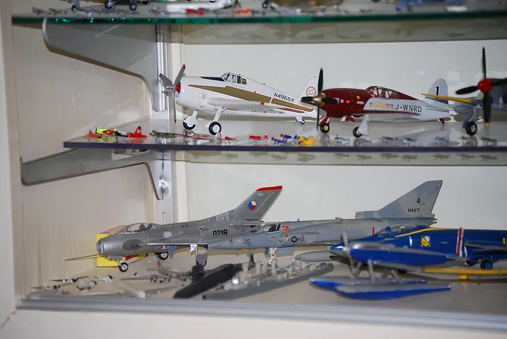 A collection of model planes on a shelf.