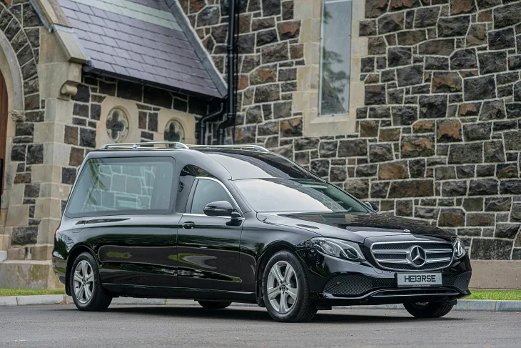 black hearse parked outside a dark brick church