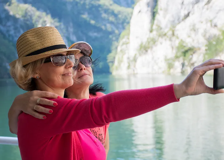 Two women in 50s standing by scenic beauty together taking a selfie together