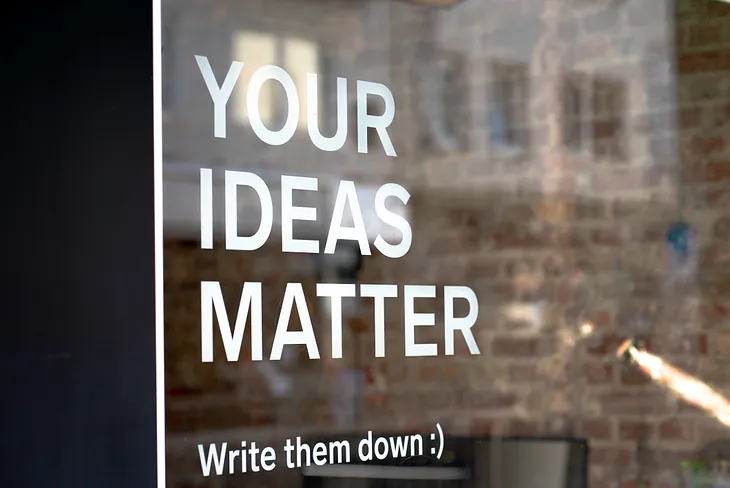 Window with sign reading “Your ideas matter. Write them down”