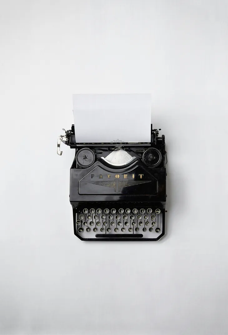 An old black typewriter with a white sheet of paper. White background.