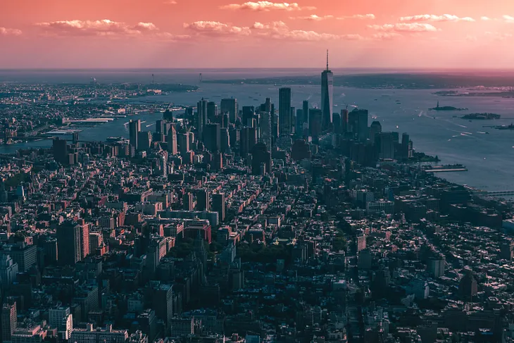 A view of a city with towering landscapes with the clouds and sunset in view