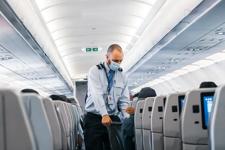 steward on flight collecting trash in the aisle