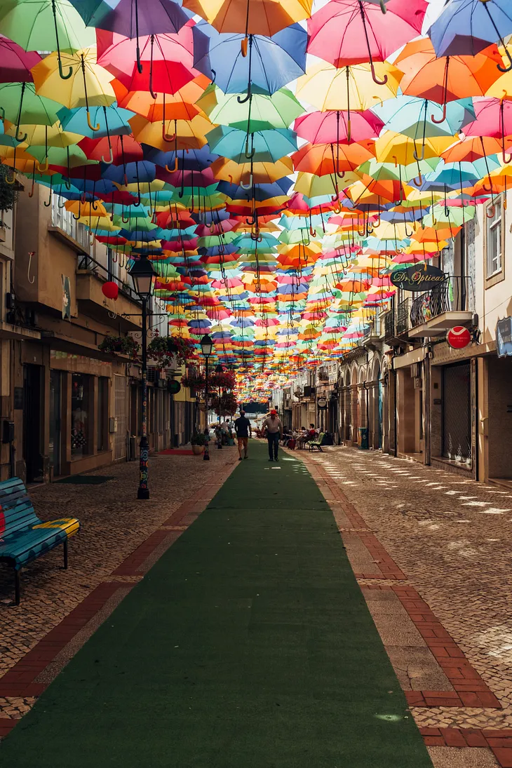 A Portuguese street with a summer shade/art installation of a myriad coloured umbrellas