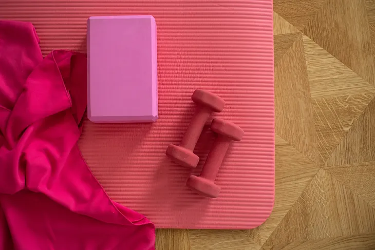 Budget-friendly home gym with exercise mat, yoga block, and dumbbells — a cost-effective fitness solution.