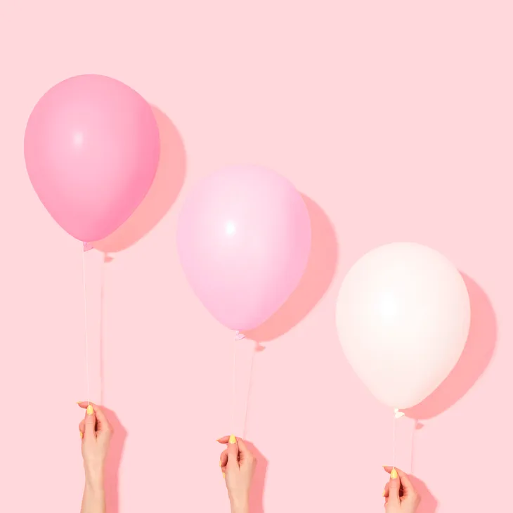 A vibrant image against a pink background featuring three balloons in various shades of pink. The balloons appear to be floating gracefully in the air, casting playful shadows on the pink backdrop. The composition reflects the lively and diverse nature of pink explored in the blog. The balloons symbolize the different emotional facets of pink, from soft and delicate to bold and energetic, inviting those with visual impairments to join in imagining the colorful scene.