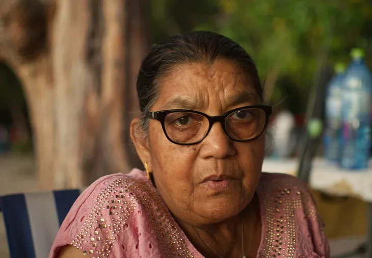 Elderly Indian woman looking pensive, wearing glasses