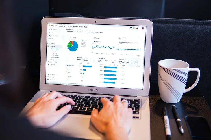 A laptop screen with a coffee cup beside it and pens in a medium post about Best Learning Practices For Data Analytics In 2023.