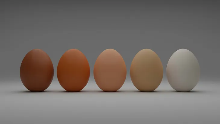 Five eggs sit upright against a grey background, their colours ranging from dark tan on the left to stark white on the right.