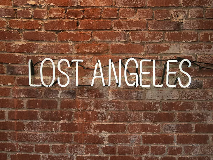 A picture of lit up words “lost Angeles” against a brick wall; a play of words to depict being lost