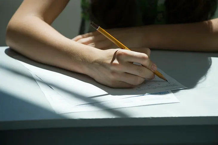 A hand holding a pencil, writing