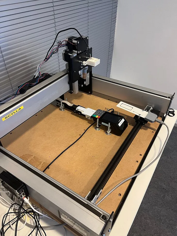 A CNC machine modified to operate the payment cards with a payment terminal in a testing laboratory.