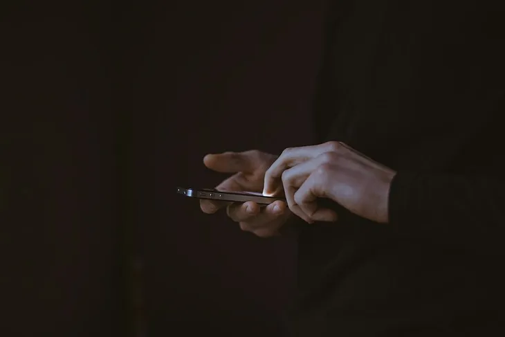 A close-up image of two hands hoding a phone