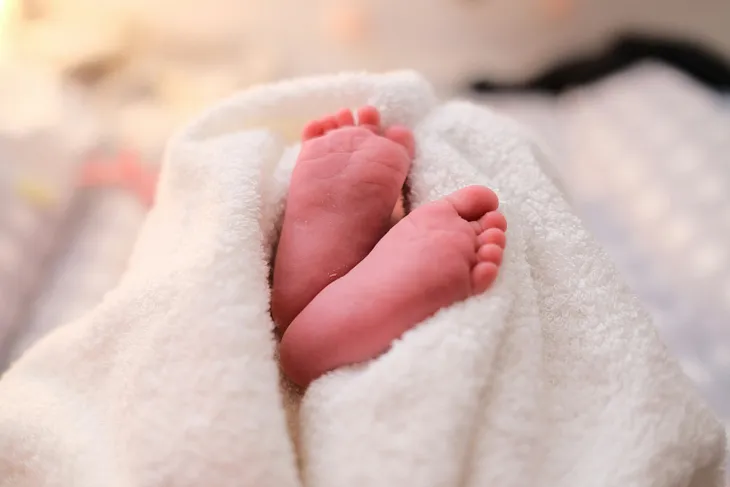 Baby’s soles peeking out of a white blanket