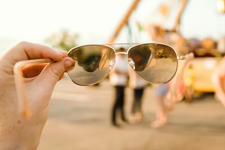 A pair of glasses held in a hand