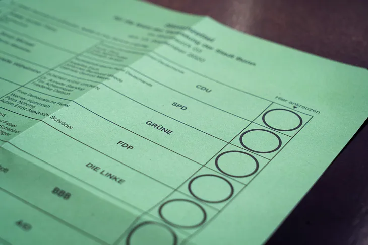 The image shows a portion of a green election ballot, with rows listing different political parties such as CDU, SPD, GRÜNE, FDP, and DIE LINKE, among others. To the right of each party name, there are empty circles where voters can mark their choices. The ballot is partially folded, and some of the text is cut off, but the structure of the document is typical for a multi-party election, likely in Germany, given the party names.