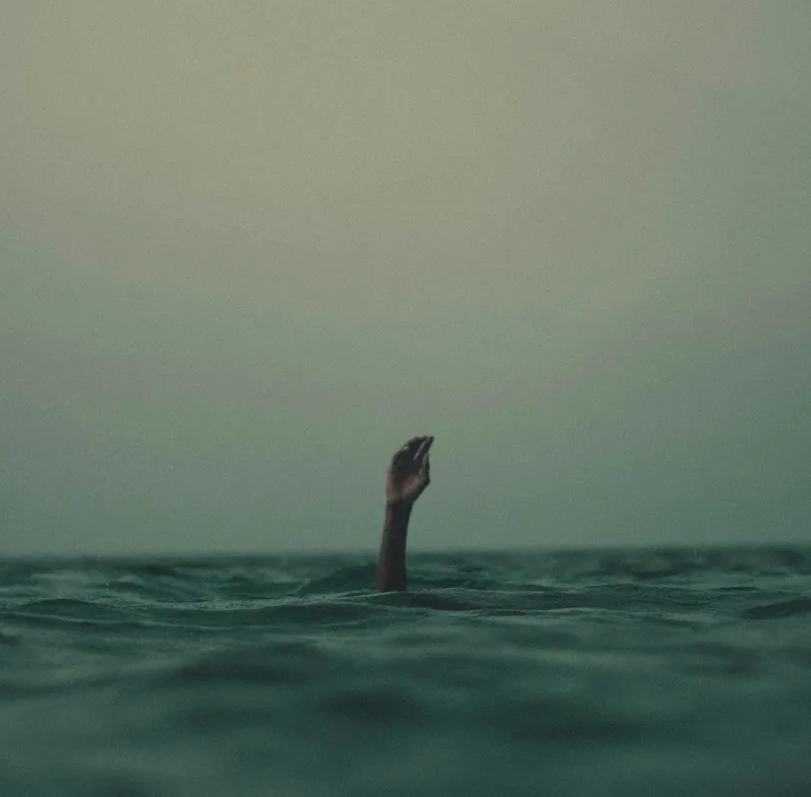 A hand reaching up from open water.