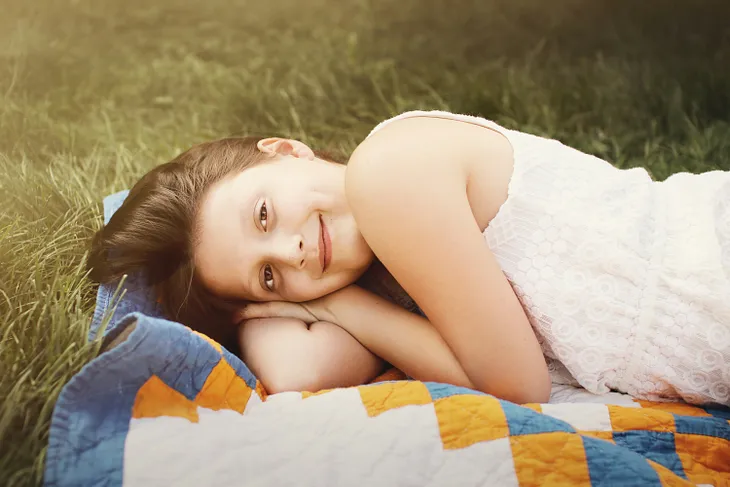 Smiling woman lying on a mat on a grass patch