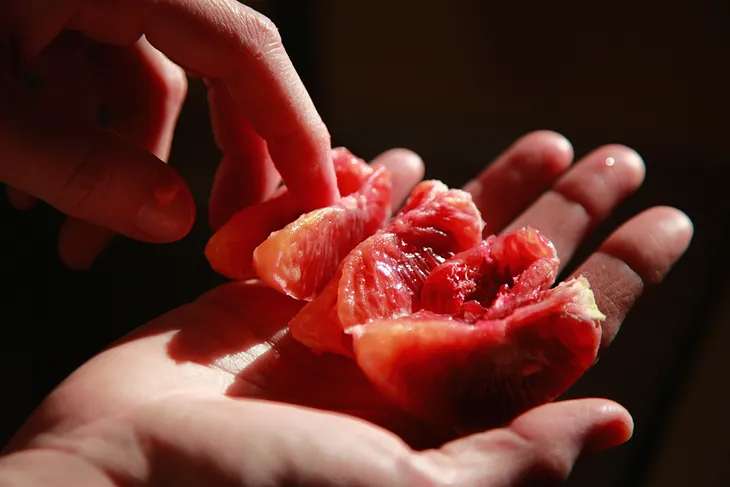 A blood orange, peeled and sectioned, juicy in the palm of a hand.