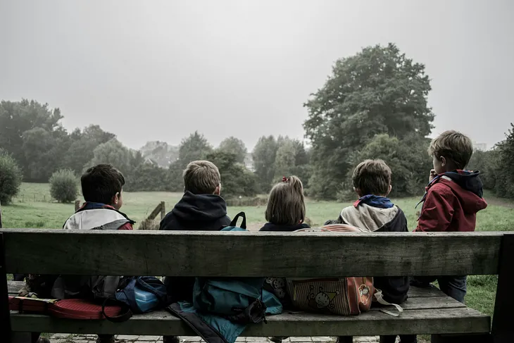 children sitting on a bench looking at nature