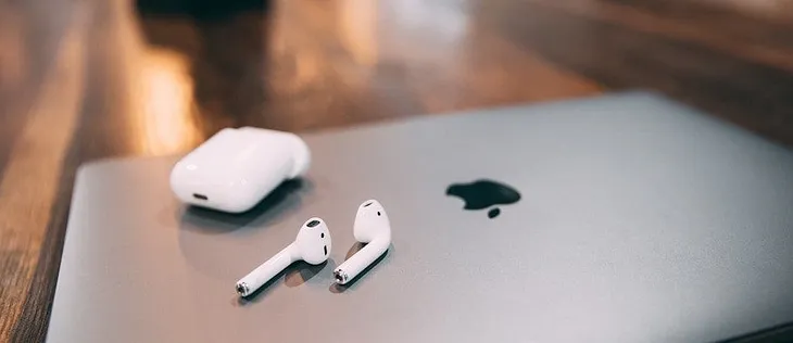 Image of laptop with a pair of airpods listening to marketing podcasts