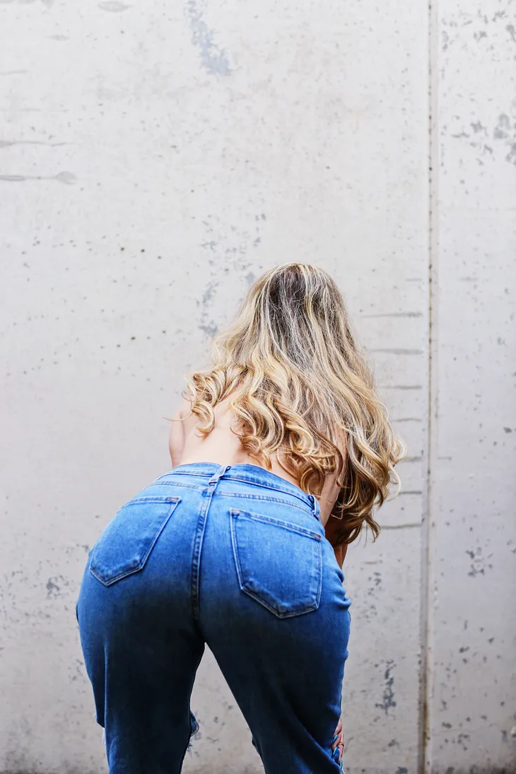 A woman bending over, presenting her rear to the camera.