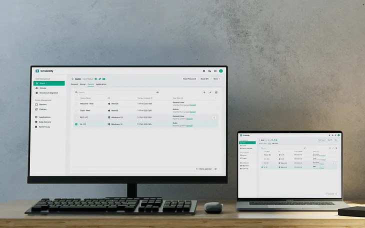 A desktop and a laptop with the C2 Identity portal displayed on the screens.