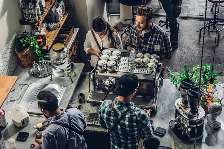 View from above the cafe counter with two employees and two customers