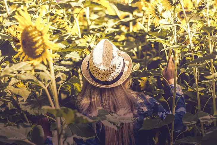 A woman standing in vegetation that is taller than she is.