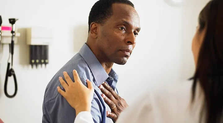 Man talking to doctor with hand on his heart for cardiovascular health