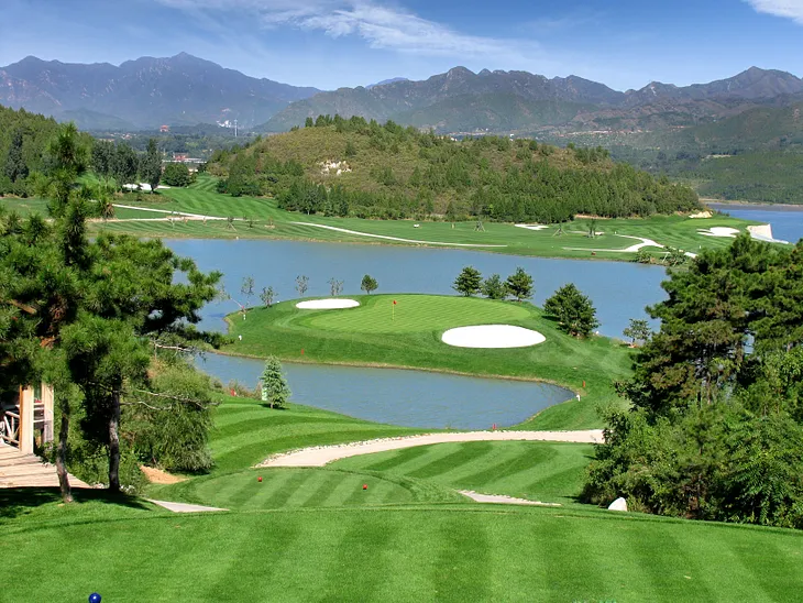 A well-manicured golf course with white sand bunkers.