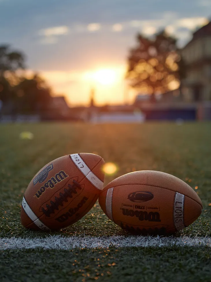 Two footballs next to each other on the field