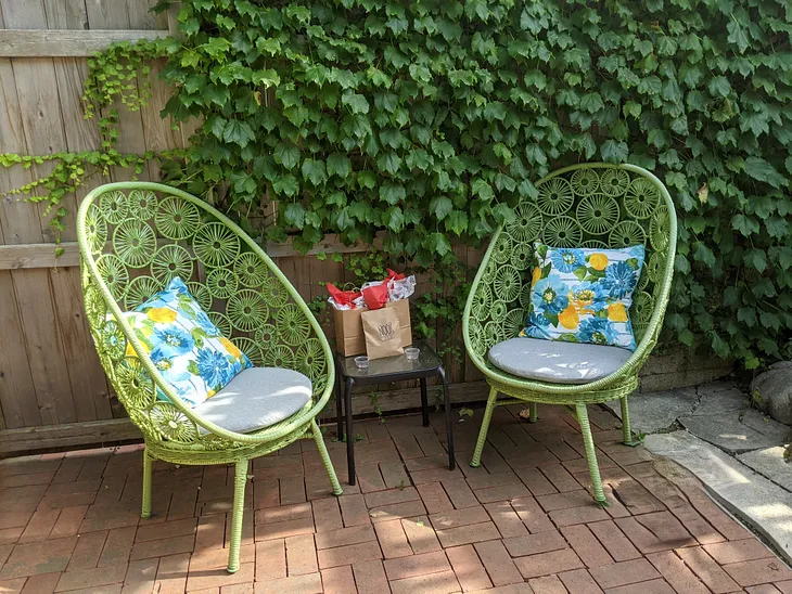 This shows two green chairs on a patio with ivy in the background.