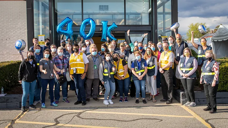 Covid-19 relief volunteers standing outside holding a 4, 0, and K balloon to spell out “40K,” to celebrate the milestone of 40,000 people vaccinated.