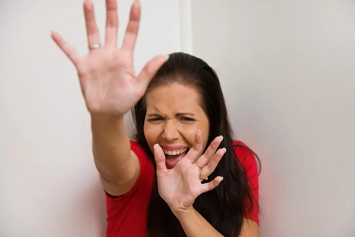 A woman in a red dress holding her hands in a defensive position.