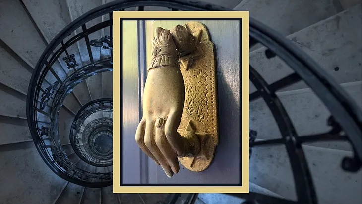 Closeup of a solid, cast brass door knocker in the shape of a lady’s left hand, also known as a westernized Hand of Fatima.