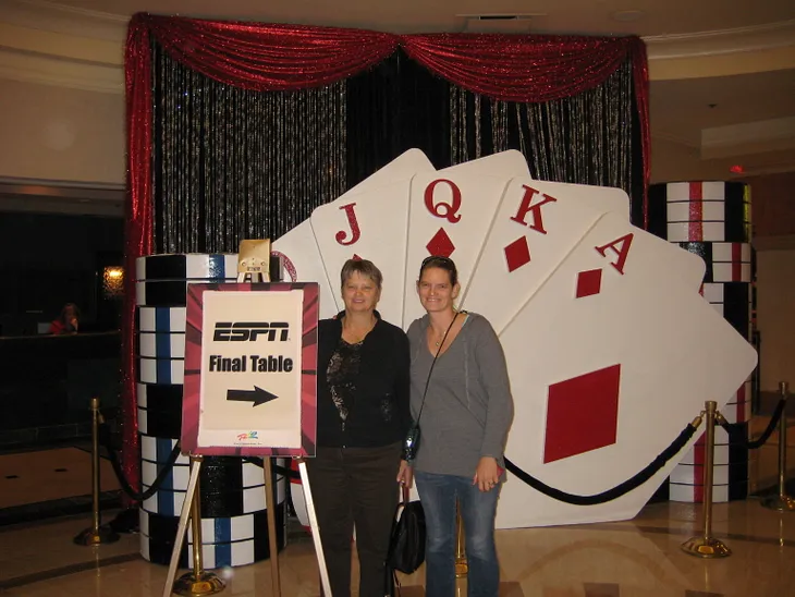 My mom and I standing in front of and ESPN Final Table sign with an arrow.