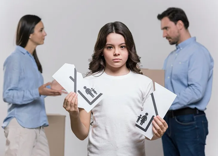 A young girl standing alone, visibly heartbroken, as she tears a family photo in half, symbolizing the deep pain caused by her parents’ frequent arguments