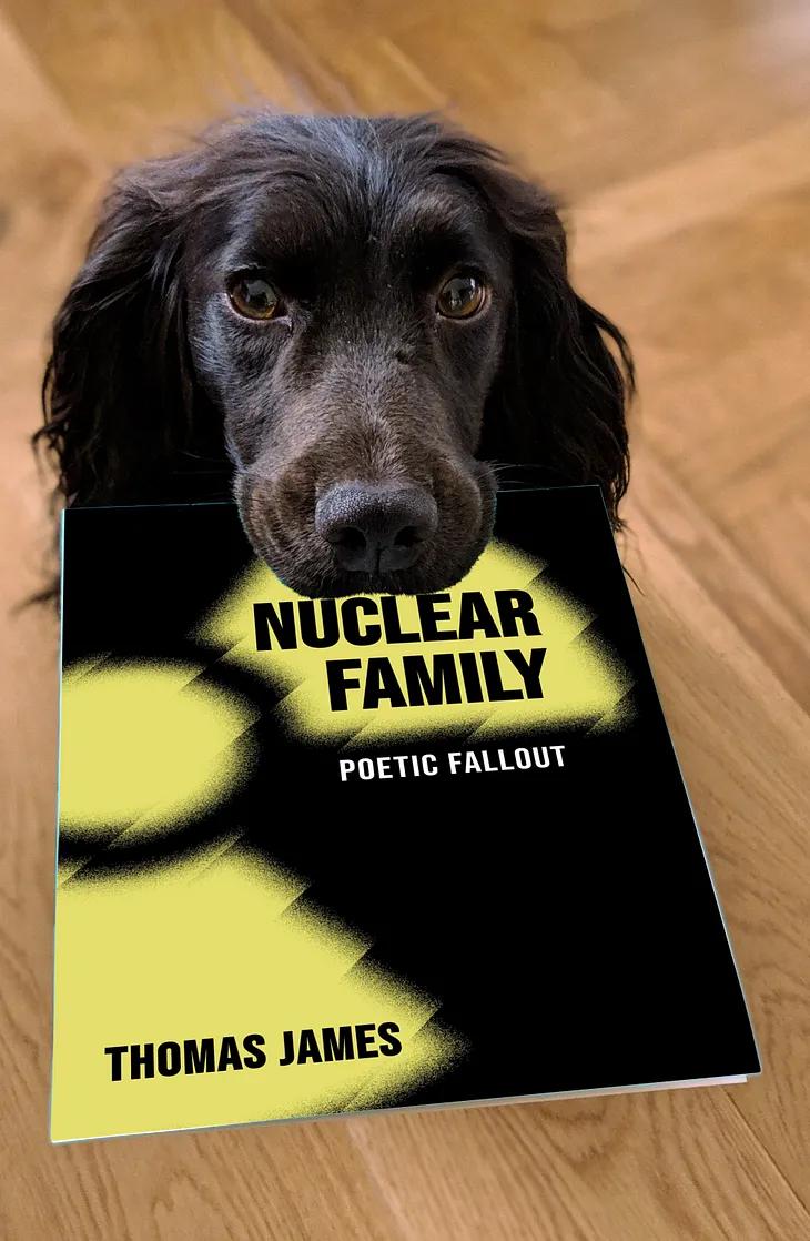 a dog holding a copy of Nuclear Family in its mouth