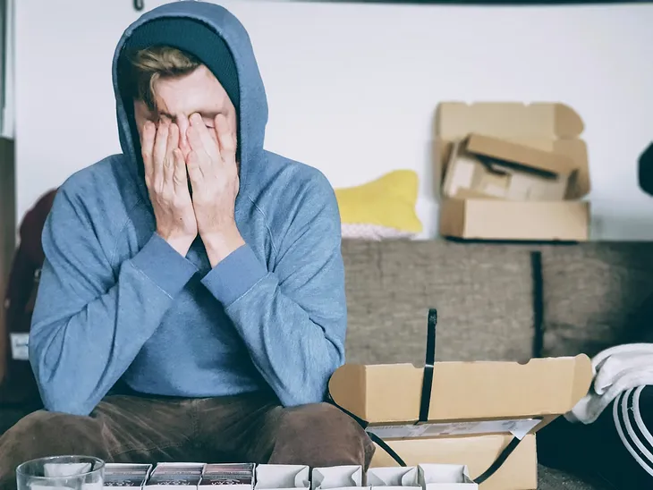 man covering face blue hoodie