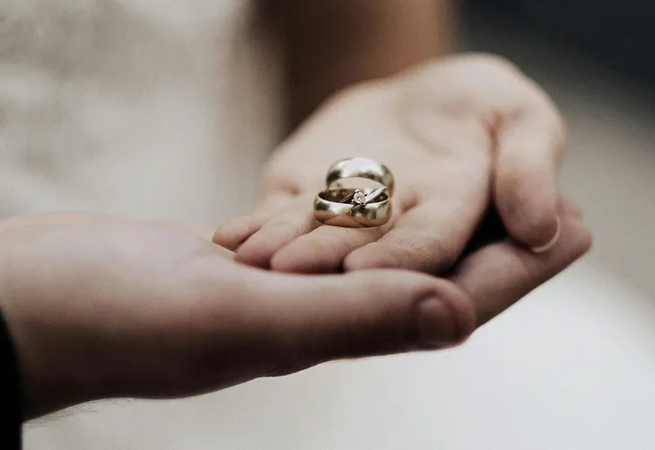 Two palms, one on top of the other with two wedding rings in the top palm