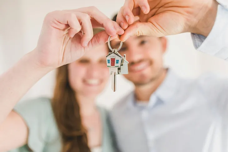 A man and a woman both holding the keys to a new house.