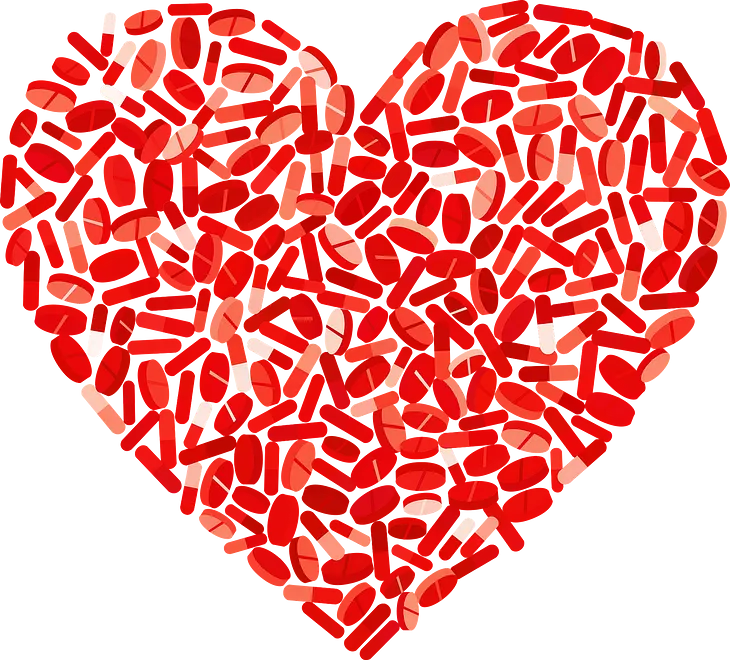 A red heart shape created using pills of different shapes and sizes.