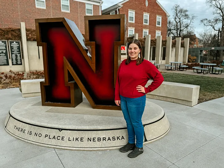 Karley smiles for a photo next to the Value of N sculpture outside the Wick Alumni Center