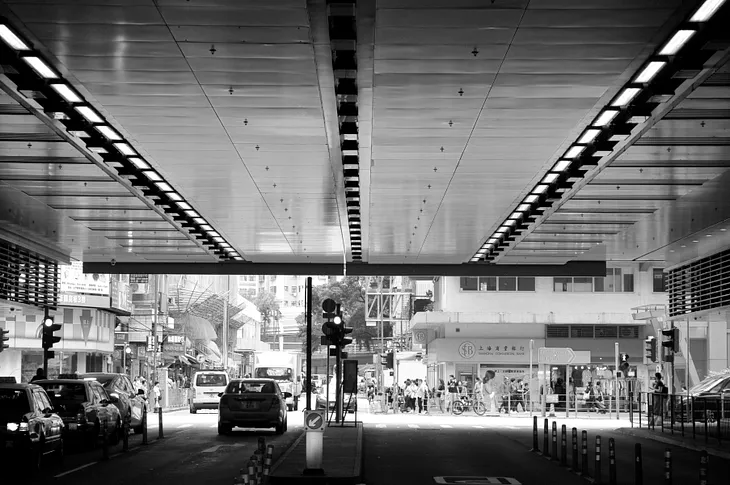 Black & White photo of the coverage of metal ceiling with illumination, viewing to the street far opposite.