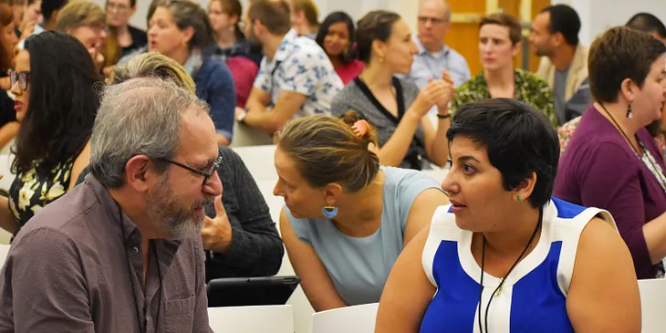 A room full of scholars engage with each other at a conference.