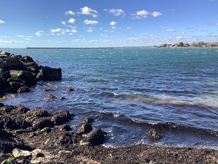 Ocean waves against the rocks of the Connecticut shore, blue skies