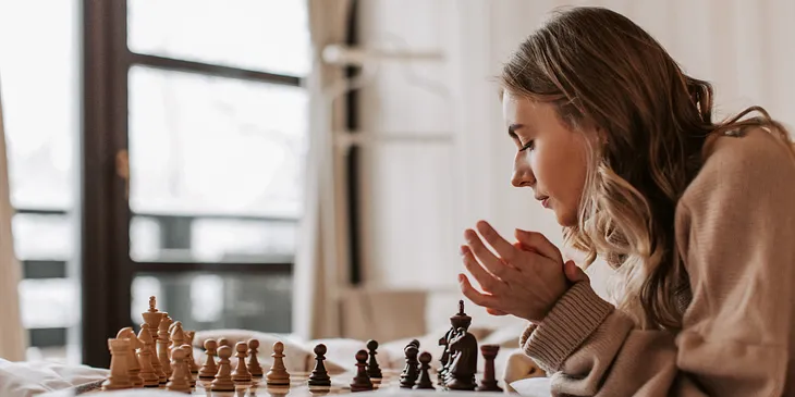 Woman gazing at chessboard on bed