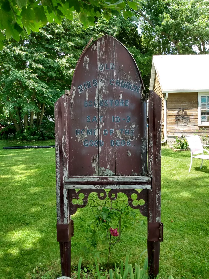 Old wooden sign by a tiny church.