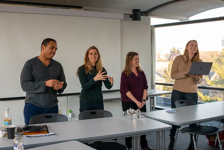 Four Assembly Fellows stand to present their work